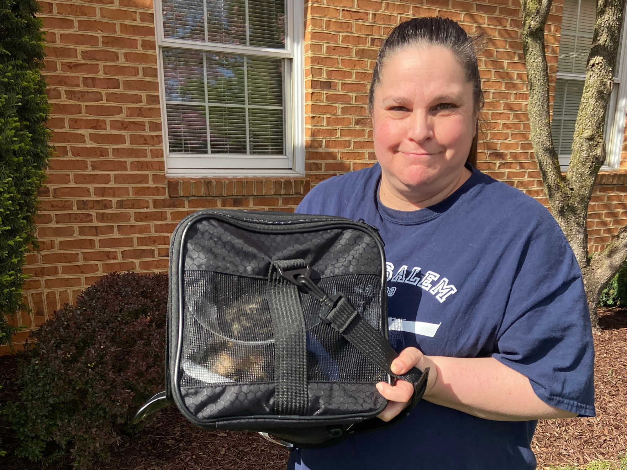 Woman holds a cat in an animal carrier