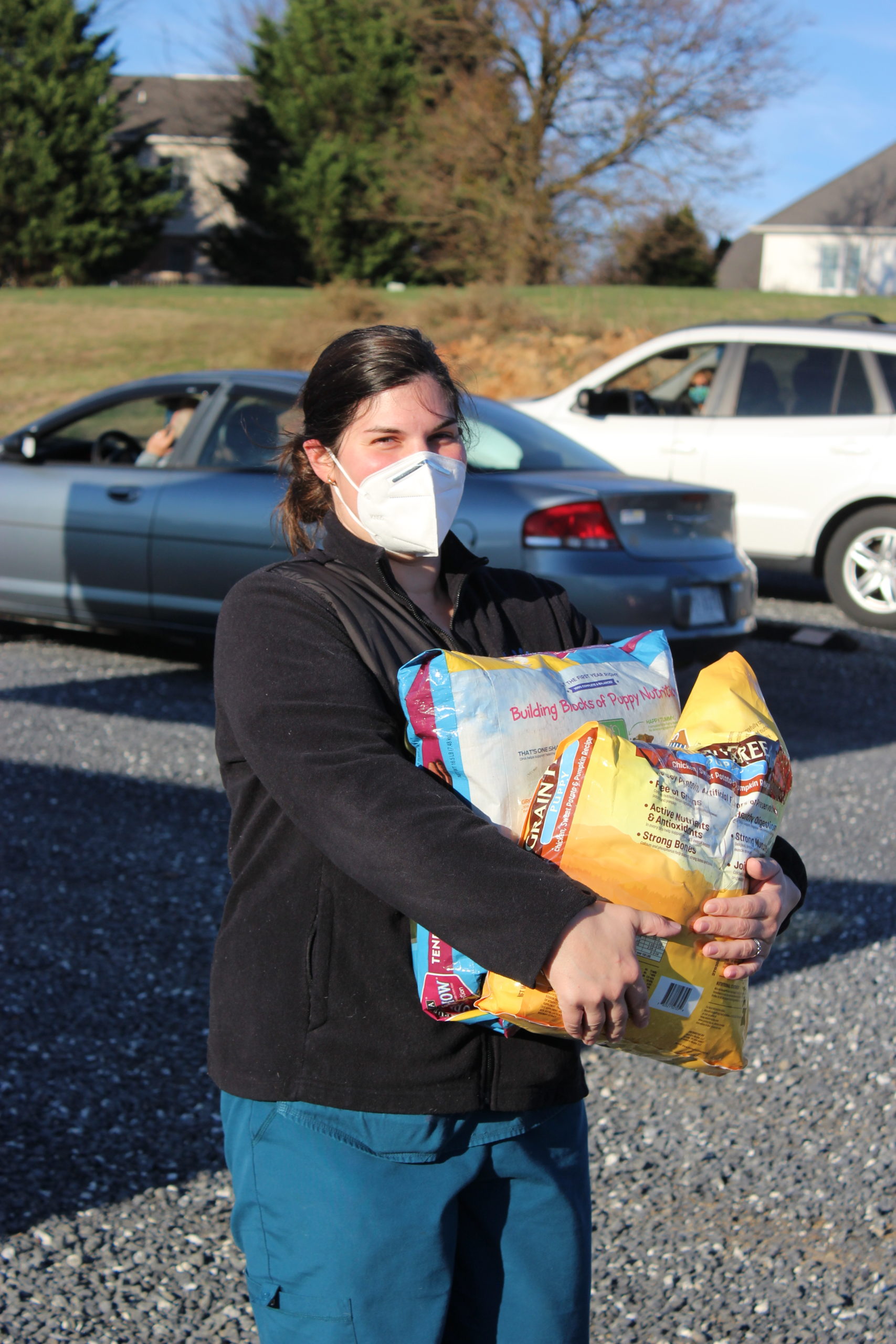 Jennifer carries two bags of dog food at pet food pantry